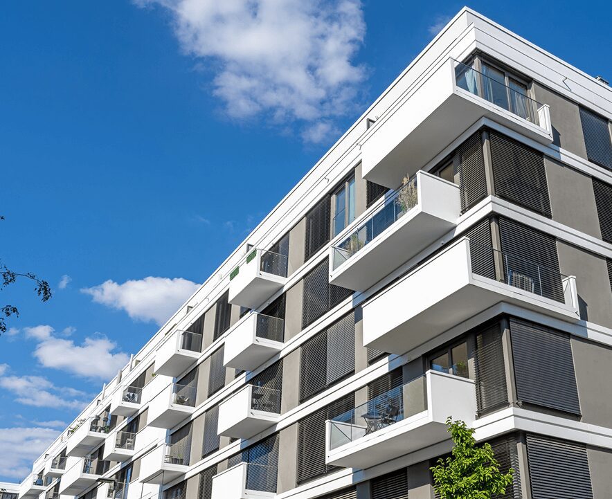 Modern apartment building with balconies under a blue sky.
